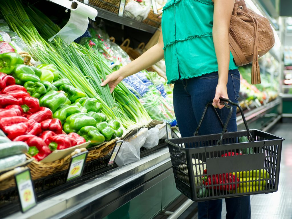 shopper picks up spring onions in fresh produce section of the supermarket