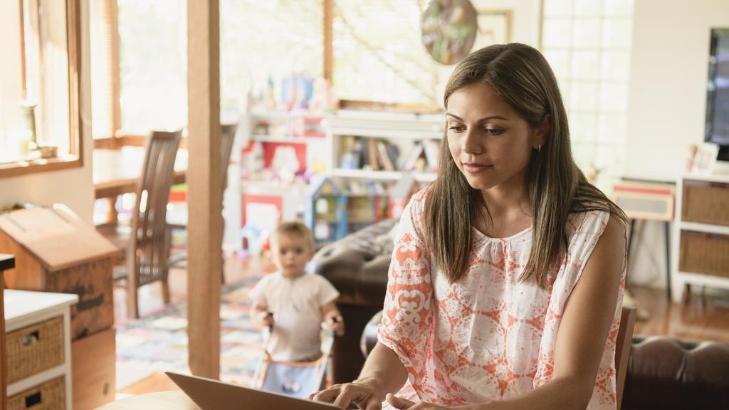 Aboriginal young woman working from home and typing on keyboard as boy watches